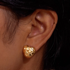 Boucles d'oreilles cœur dorées avec texture tressée portées sur le lobe de l'oreille