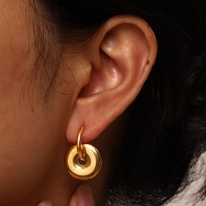 Close-up of a minimalist gold geometric hoop earring with a polished mirror finish on model