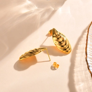 Close-up of gold stainless steel stud earrings with textured wavy croissant shell pattern