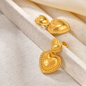 Boucles d'oreilles cœur dorées double couche avec texture torsadée sur fond beige