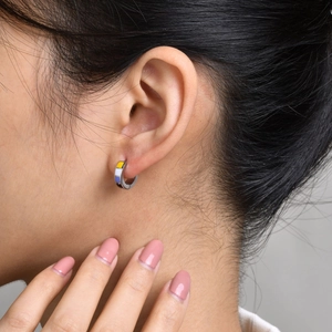 Detail of a stainless steel hoop earring with non-binary pride flag enamel colors