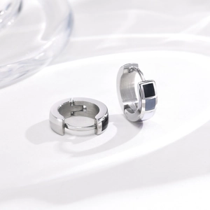 Detailed macro view of silver steel hoop earrings with black grey white enamel pattern
