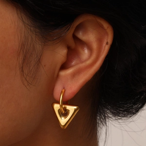 Macro view of a gold-plated stainless steel triangular geometric earring on ear