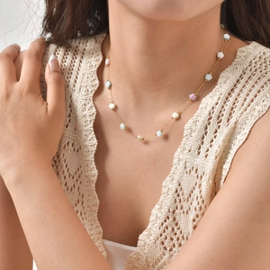 Close-up of golden collar necklace featuring colorful macaron star beads on a female model