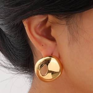 Detailed view of oversized golden geometric earrings with a teardrop cutout design