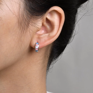 Close-up of a stainless steel hoop earring with blue, pink and white enamel pattern