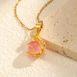 Nahaufnahme von rosa Katzenauge-Anhänger mit gedrehten goldenen Metallspiralen