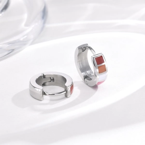 Detail of silver stainless steel hoop earrings with colorful enamel square patterns