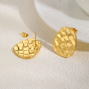 Close-up of golden braided wave stud earrings with 18k texture on white surface