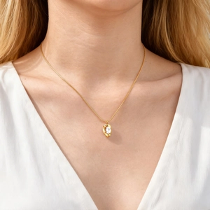 Detail of a gold stainless steel necklace with oval white zircon pendant on model