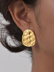 Close-up of golden wavy woven stud earrings featuring a textured 18K gold finish on a model