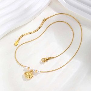 Macro detail of 18K gold fish pendant with white pearls and sleek snake chain