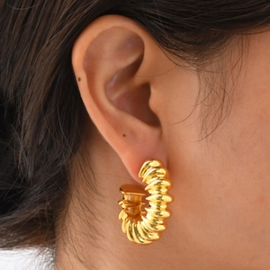Detailed close-up of a gold C-shaped earring with elegant spiral texture on a model's ear