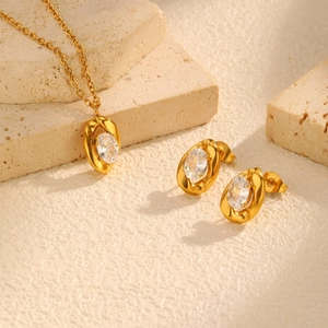 Detail view of gold oval zircon necklace and earring set on minimalist stone background