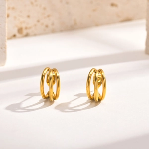 Détail de boucles d'oreilles triple anneaux entrelacés plaqués or 18 carats sur pierre