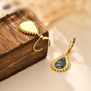 Detail of gold teardrop earrings featuring iridescent abalone shell inlay on wood