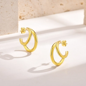 Détail de boucles d'oreilles doubles anneaux dorées 18 carats sur présentoir en pierre