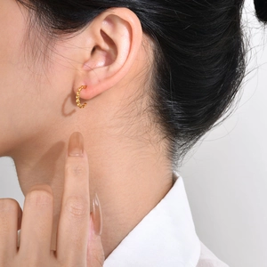 Gros plan de boucles d'oreilles créoles perlées dorées en C portées pour un look chic