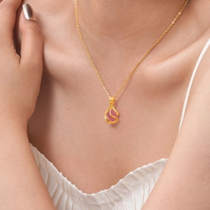 Nahaufnahme der goldenen Halskette mit rosa Tropfenstein und gedrehtem Metallanhänger