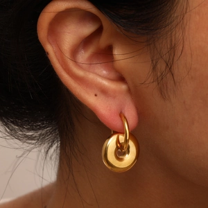 Polished gold geometric hoop earrings with chunky donut pendant shown on model ear