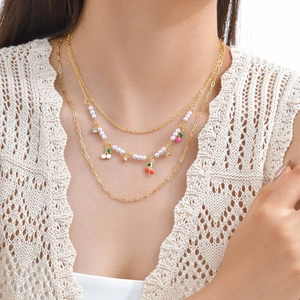 Detailed close-up of a triple-layered cherry pendant necklace with pearls on a model