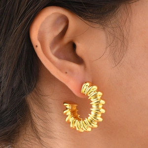 Fashionable gold-plated C-shaped ribbed hoop earrings worn by a female model