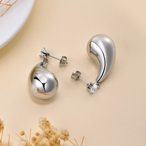Vue détaillée de boucles d'oreilles argentées avec zircons ronds et pendants polis