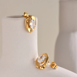 Close-up of gold oval cubic zirconia earrings on a minimalist white ceramic tray
