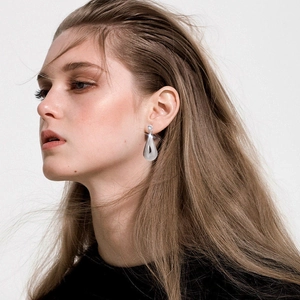 Détail de boucles d'oreilles goutte argentées avec zircon portées par un mannequin