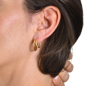 Gros plan de boucles d'oreilles doubles créoles plaquées or 18k sur le lobe de l'oreille