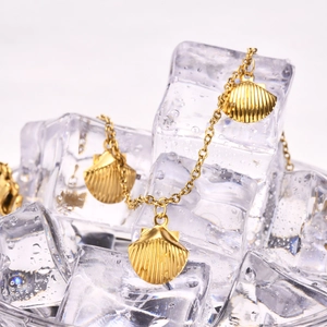 Macro shot of gold shell pendants on a stainless steel chain anklet over ice