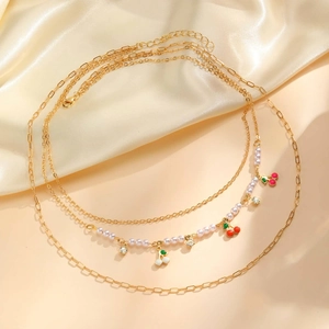 Three-layer gold cherry necklace set with faux pearls and rhinestones on silk background