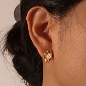 Golden oval stud earrings with clear cubic zirconia on a model for minimalist luxury style