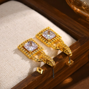 Macro shot of gold lock earrings with emerald cut zircon and pavé rhinestone detailing