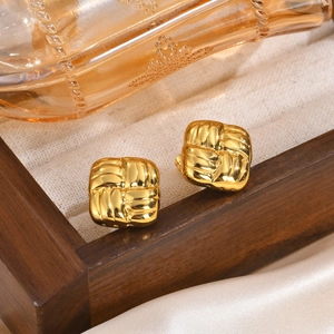 Boucles d'oreilles carrées tressées dorées présentées sur un écrin à bijoux