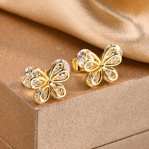 Detail of gold butterfly earrings with zircon inlay on a textured jewelry box