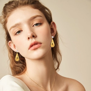 Gros plan de boucles d'oreilles goutte d'eau dorées avec zircon portées par un mannequin