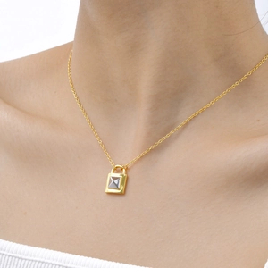 Detail einer minimalistischen Goldkette mit silbernem Pyramiden-Schlossanhänger am Model