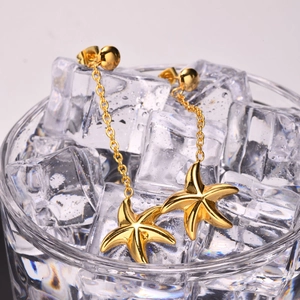 Boucles d'oreilles étoiles de mer dorées avec de longues chaînes sur verre glacé