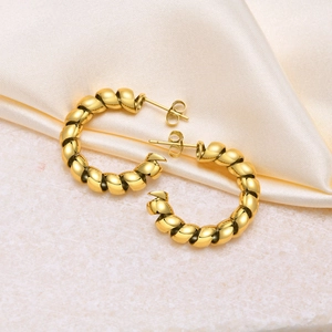 Close-up of golden stainless steel twisted C-hoop earrings on elegant white satin