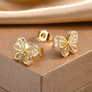 Macro detail of gold butterfly stud earrings with zircon stones and hollow design