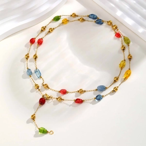 Dettaglio della collana con pietre colorate, perle dorate e chiusura regolabile
