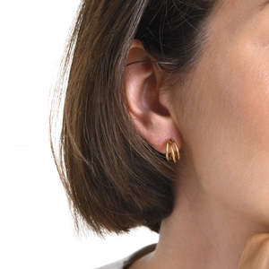 Gros plan d'une femme portant des boucles d'oreilles créoles triple rang plaqué or 18k