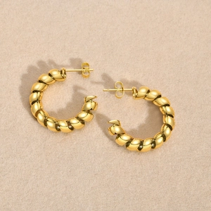 Detailed view of golden stainless steel twisted hoop earrings with a polished mirror finish
