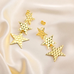 Detail of gold star drop earrings featuring textured rhombus pattern on satin fabric