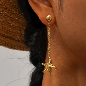 Boucles d'oreilles étoiles de mer dorées sur un mannequin au style de vacances