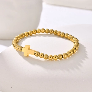 Détail du bracelet en perles dorées en acier inoxydable avec pendentif croix minimaliste