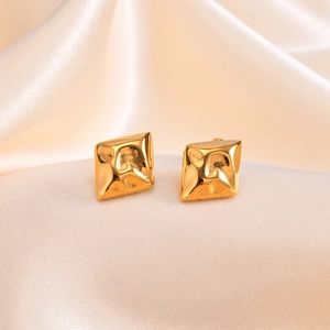 Golden square earrings with hammered irregular texture on champagne satin fabric background