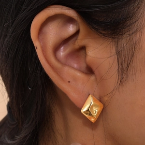 Irregular hammered gold diamond shape stainless steel stud earrings on model ear