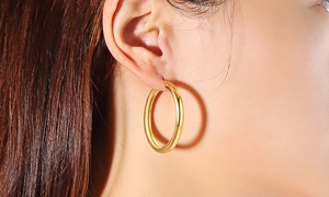 Nahaufnahme einer Frau mit großen, goldglänzend polierten Creolen in elegantem Stil